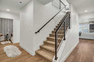 Staircase with recessed lighting and hardwood / wood-style floors