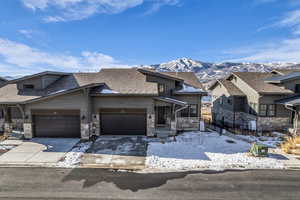 View of front of home featuring stone siding, concrete driveway, a shingled roof, and a mountain view