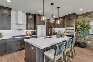 Kitchen featuring a breakfast bar area, dark wood finish cabinets, pendant lighting, and light wood-style floors