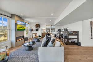 Living room featuring a large fireplace, light wood-type flooring, and recessed lighting