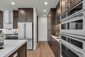 Kitchen featuring dark wood finish cabinets, white appliances, recessed lighting, light stone countertops, and light wood-style floors