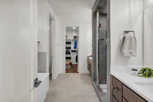 Full bathroom with vanity, a walk in closet, a stall shower, and recessed lighting