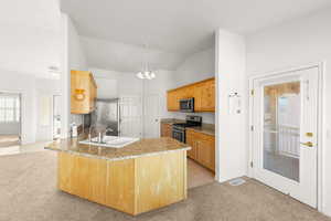 Kitchen featuring light colored carpet, a peninsula, light tile patterned floors, a chandelier, and vaulted ceiling
