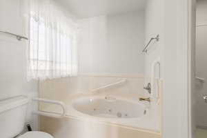 Full bathroom featuring a tub with jets and toilet