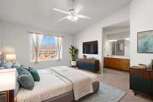Bedroom featuring light carpet, vaulted ceiling, ceiling fan, and ensuite bath