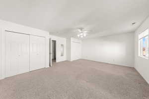 Unfurnished bedroom with multiple closets, light carpet, and a ceiling fan