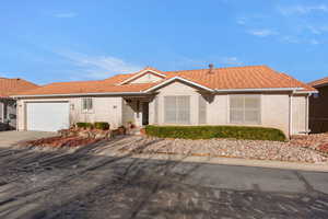 Single story home with stucco siding, a tiled roof, concrete driveway, and an attached garage