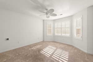Empty room featuring ceiling fan and carpet flooring