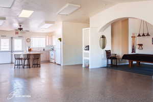 Kitchen featuring pool table, light countertops, a breakfast bar, open floor plan, and white appliances