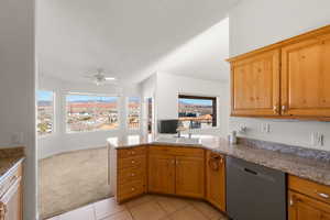 Kitchen with a peninsula, dishwasher, light colored carpet, light tile patterned floors, and light stone countertops