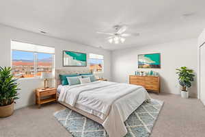 Bedroom with light colored carpet, ceiling fan, a mountain view, and multiple windows