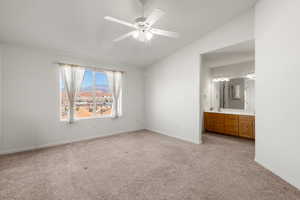 Unfurnished bedroom featuring lofted ceiling, light carpet, ceiling fan, ensuite bathroom, and a mountain view