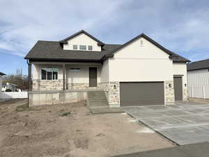 View of front facade featuring a porch, stone siding, concrete driveway, and a shingled roof