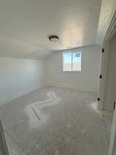 Empty room with vaulted ceiling and a textured ceiling