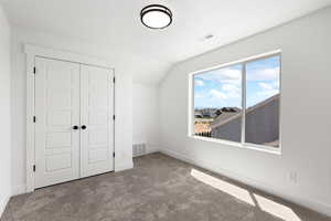 Unfurnished bedroom featuring lofted ceiling, carpet flooring, and a closet