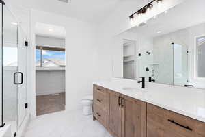 Full bath featuring a walk in closet, a marble finish shower, and vanity