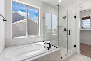 Full bathroom featuring a marble finish shower, a garden tub, and marble look tiles