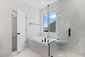 Bathroom featuring a bath and a marble finish shower