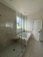 Bathroom featuring a stall shower, a garden tub, light tile patterned flooring, and a textured ceiling