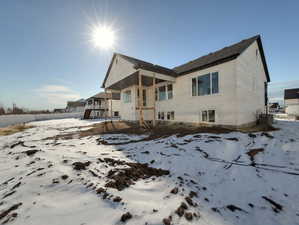 Snow covered rear of property with a patio area