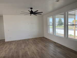 Unfurnished room featuring dark wood-style floors, ceiling fan, and a textured ceiling