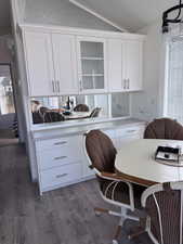 Kitchen with white cabinetry, glass insert cabinets, light countertops, and vaulted ceiling