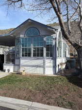 View of side of home with a sunroom and a yard