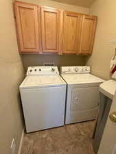 Laundry room with a textured wall, separate washer and dryer, and cabinet space