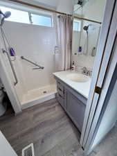 Full bathroom featuring vanity, dark wood-type flooring, and a shower stall