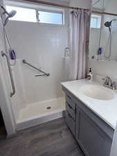 Full bathroom with vanity, a stall shower, dark wood finished floors, and plenty of natural light