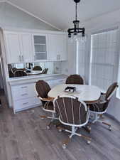 Dining space with vaulted ceiling, wood finished floors, and a chandelier