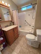Bathroom featuring vanity, a textured wall, shower / bath combination with curtain, and light tile patterned floors
