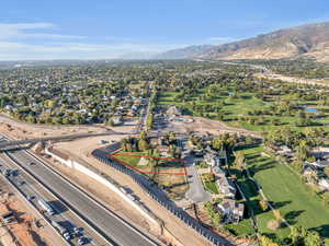 Aerial perspective of suburban area featuring property boundaries highlighted, a golf club, and a water and mountain view