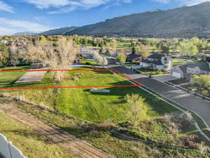 Aerial perspective of suburban area featuring property boundaries highlighted and a mountain backdrop
