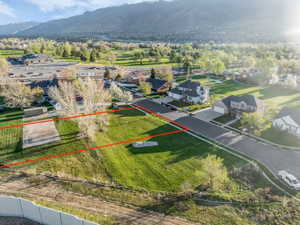 Aerial view of residential area featuring property parcel outlined and a mountain backdrop