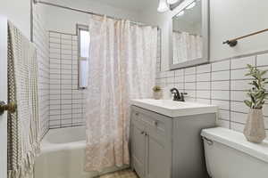 Bathroom featuring shower / tub combo, vanity, and tile walls