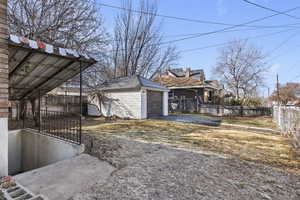 View of side of home with driveway, a detached garage, and an outbuilding