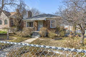 Ranch-style home featuring a fenced front yard, brick siding, and a chimney