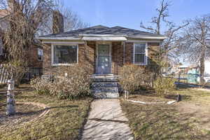 View of front of house with a chimney, a shingled roof, and brick siding