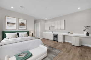 Bedroom featuring light wood-style flooring, beverage cooler, and recessed lighting
