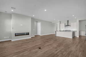 Unfurnished living room with a glass covered fireplace, recessed lighting, and dark wood-type flooring