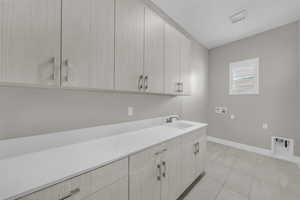 Laundry room featuring hookup for a washing machine, cabinet space, and light tile patterned floors