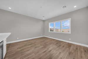 Unfurnished living room featuring light wood finished floors, wine cooler, and recessed lighting