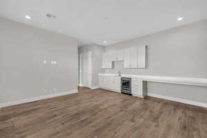 Kitchen featuring light countertops, white cabinets, wine cooler, dark wood-style floors, and recessed lighting