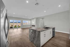 Kitchen featuring freestanding refrigerator, dark wood-type flooring, light stone countertops, open floor plan, and white cabinets