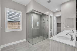 Full bathroom featuring a shower stall, light tile patterned floors, double vanity, and a spacious closet