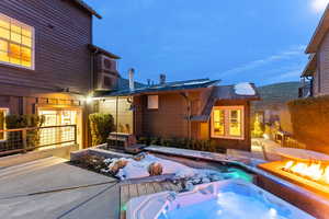 Back of property featuring a patio, an outdoor fire pit, and an outdoor hot tub