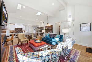 Living area with a skylight, light wood-type flooring, vaulted ceiling, and recessed lighting