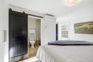Bedroom featuring wood finished floors, a barn door, and ensuite bathroom