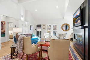Living room with a fireplace, light wood-type flooring, vaulted ceiling, and recessed lighting